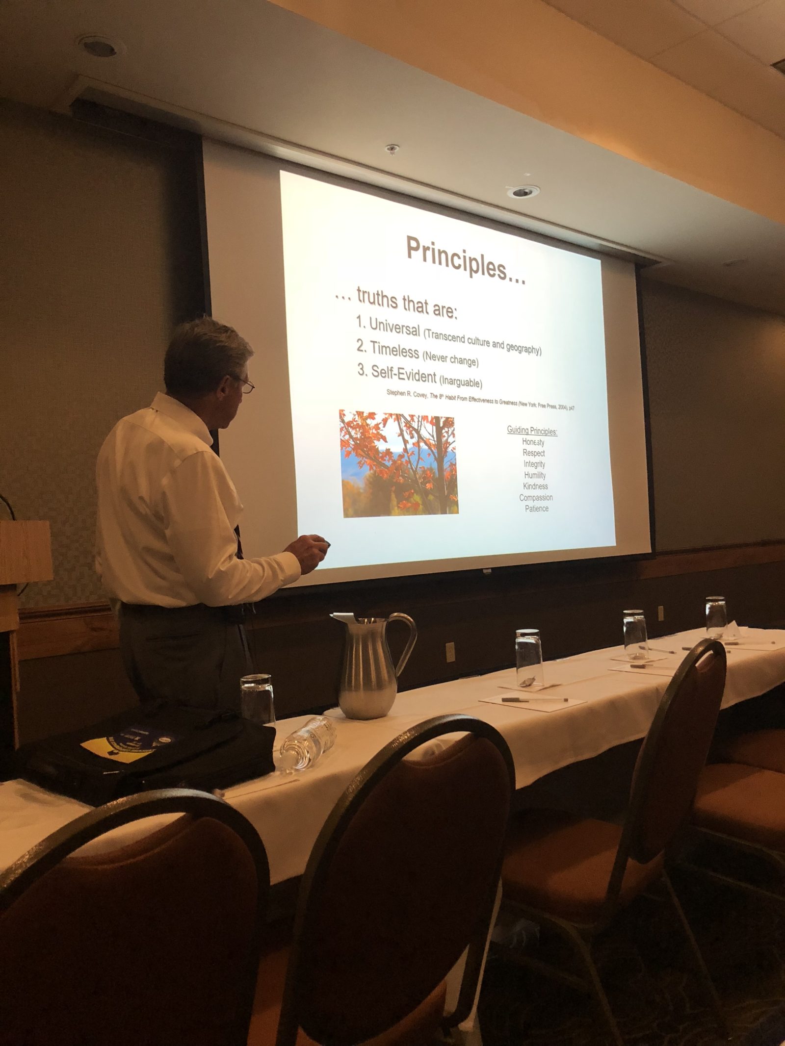 A person presenting a PowerPoint in a conference room.