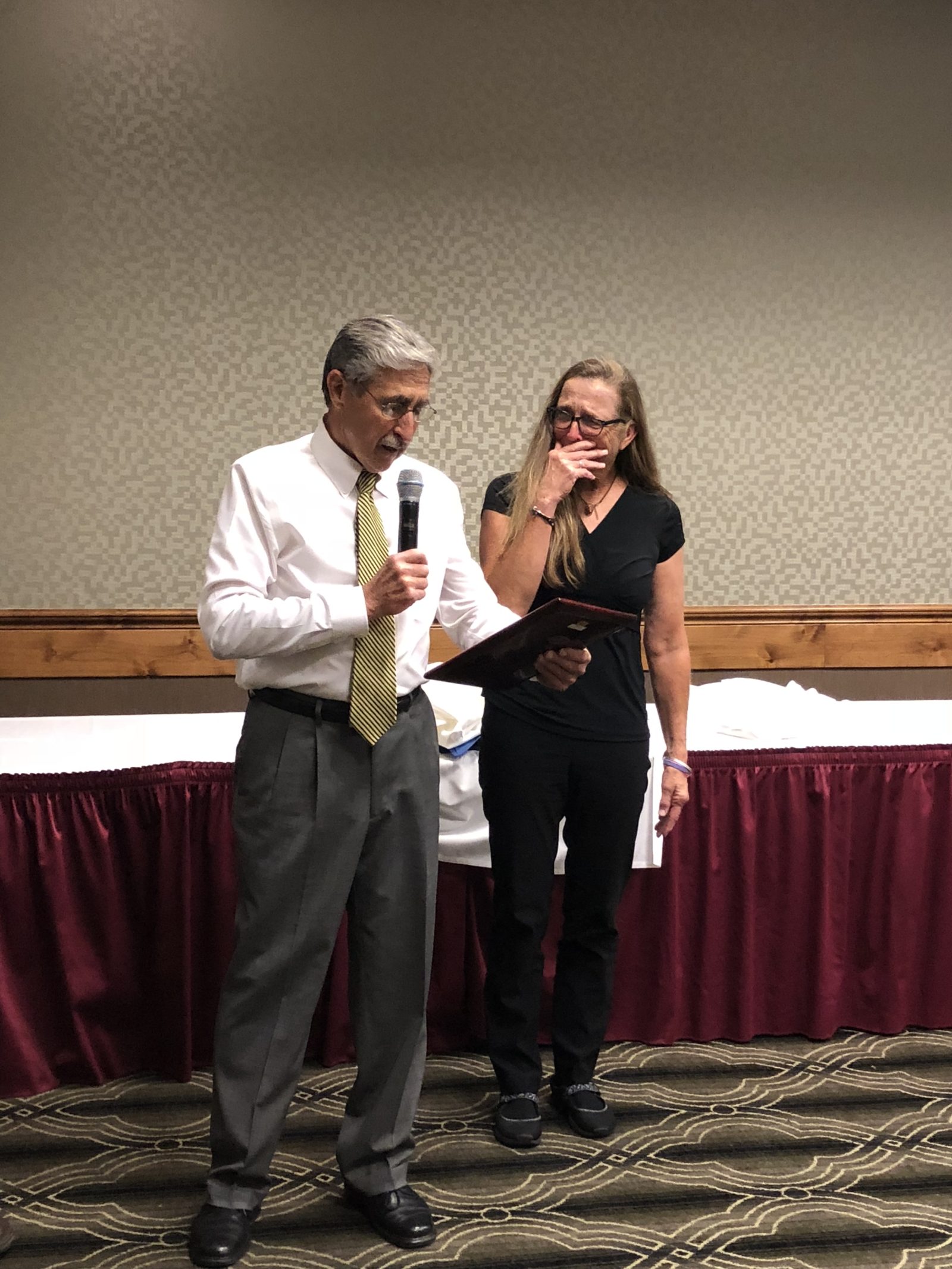 Two people laughing and enjoying a moment at an indoor event.