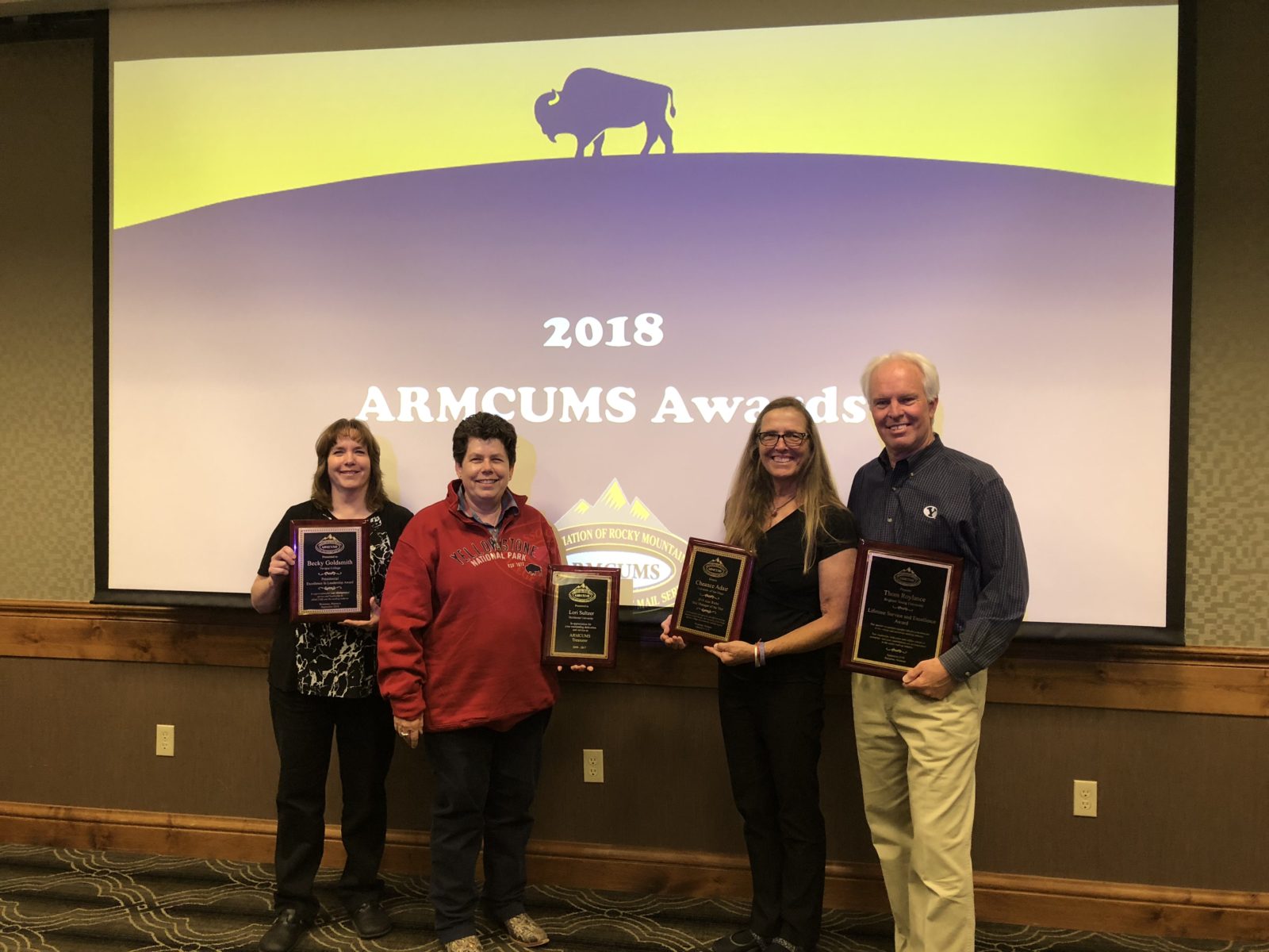 Four people posing with awards at the 2018 Bison Awards event.