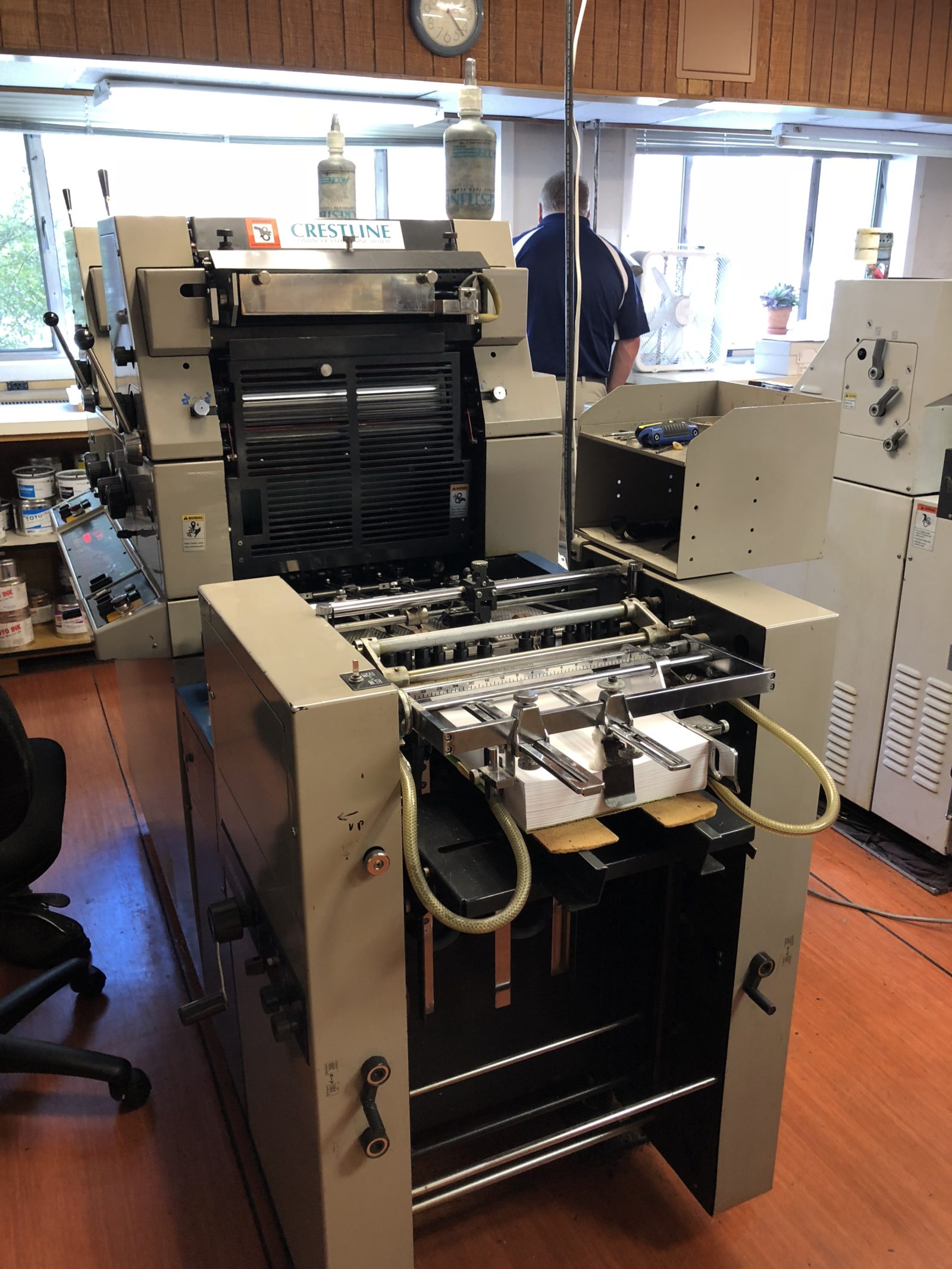 An industrial printing press in a workshop setting.