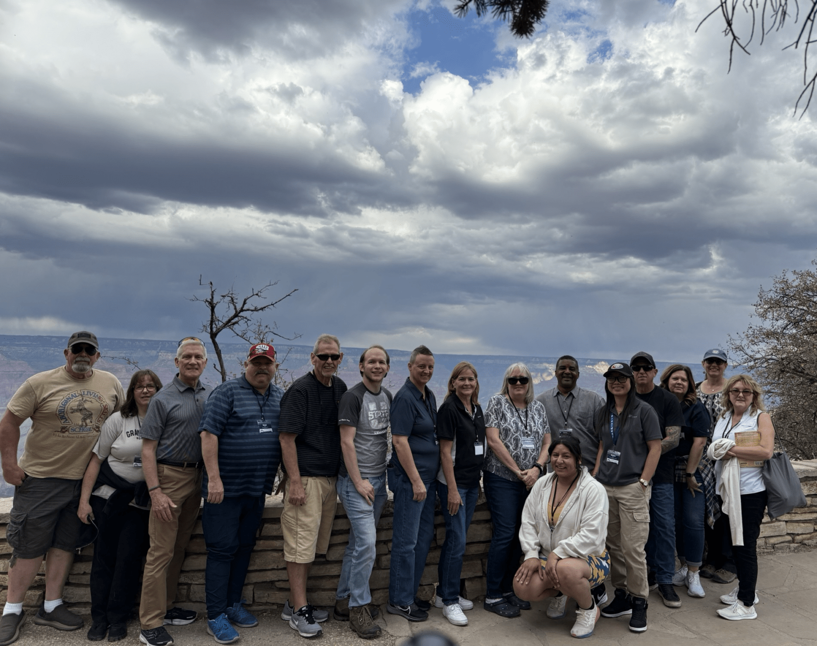 Group of people posing outdoors under a cloudy sky.